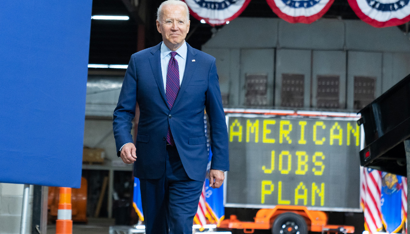 Joe Biden walking with "American Jobs Plan" sign