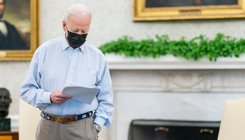 Joe Biden with black mask on, looking at papers in hand