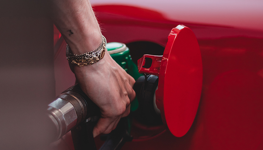 Person filling up red car with petrol/gasoline