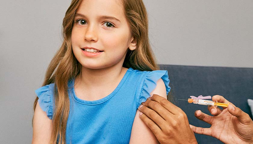 Young girl with a blue shirt on getting a vaccine